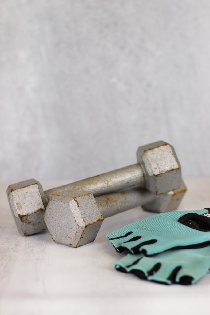 2 five pound dumb bell weights with a pair of turquoise weight lifting gloves 