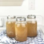 jars of canned beef bone broth on a blue and white tea towel