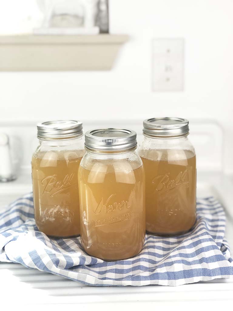 jars of canned beef bone broth on a blue and white tea towel