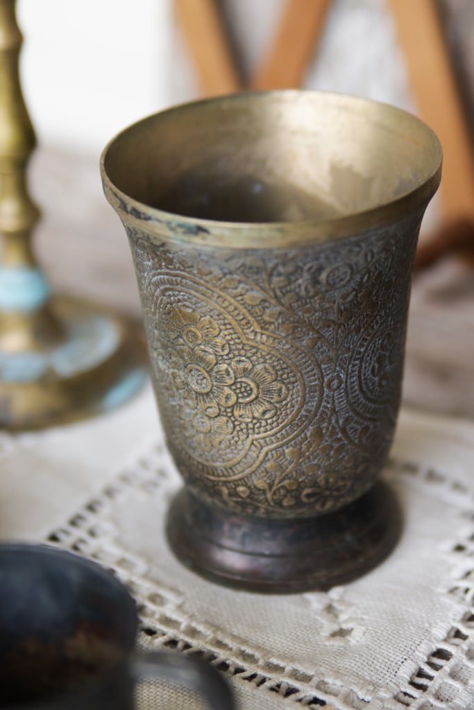 a vintage decorative brass vase on an antique white table runner