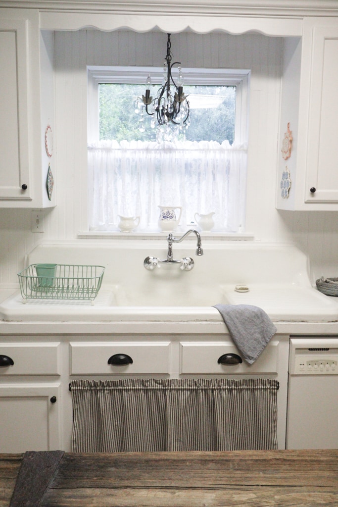 high back cast iron sink in a white kitchen with a antique chandelier