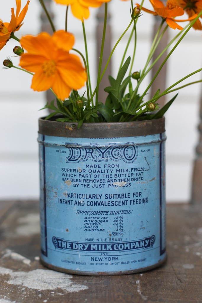 a vintage blue dryco powdered milk can sitting on a paint splattered chair
