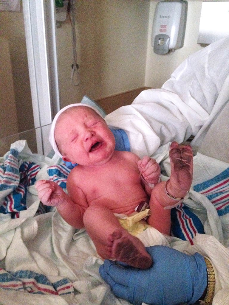 Nurse holding newborn baby with ink on it's feet.