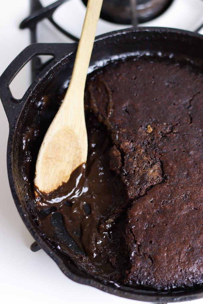 brownie pudding in a cast iron skillet sitting on a white vintage stove